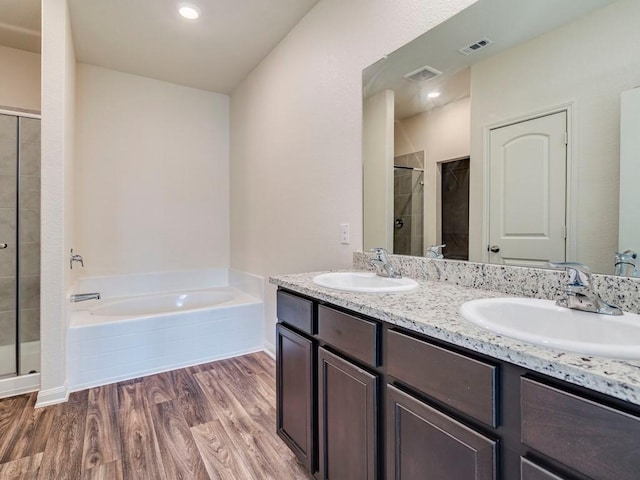 full bathroom with a sink, visible vents, wood finished floors, and a shower stall