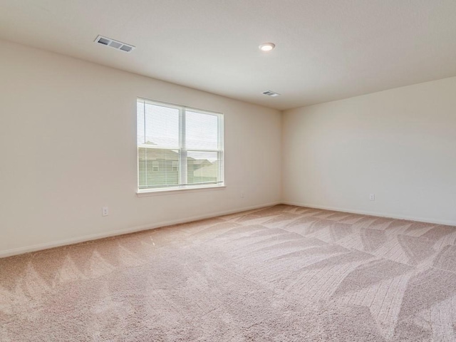 empty room with visible vents, baseboards, and light colored carpet