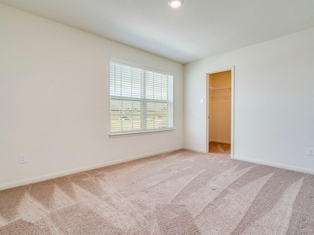 empty room featuring light colored carpet and baseboards