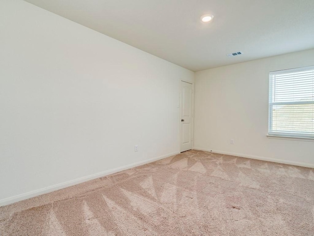 empty room with light colored carpet, visible vents, and baseboards