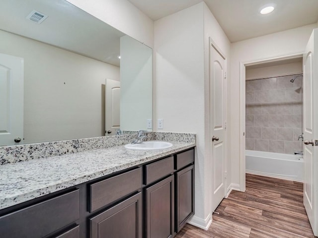 bathroom featuring visible vents, baseboards, bathing tub / shower combination, wood finished floors, and vanity