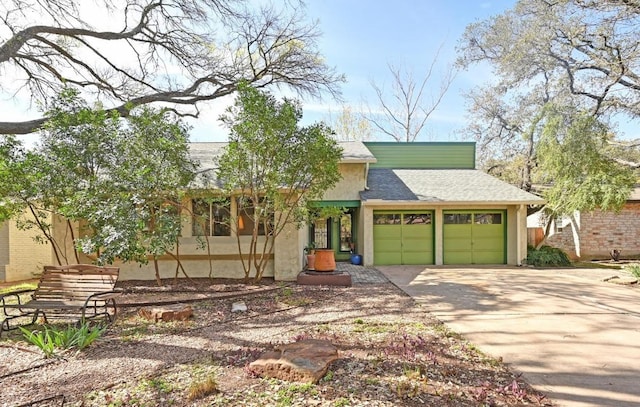 view of front of house with stucco siding, an attached garage, driveway, and roof with shingles