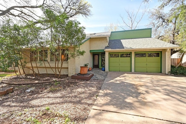 mid-century inspired home with a shingled roof, a garage, driveway, and stucco siding