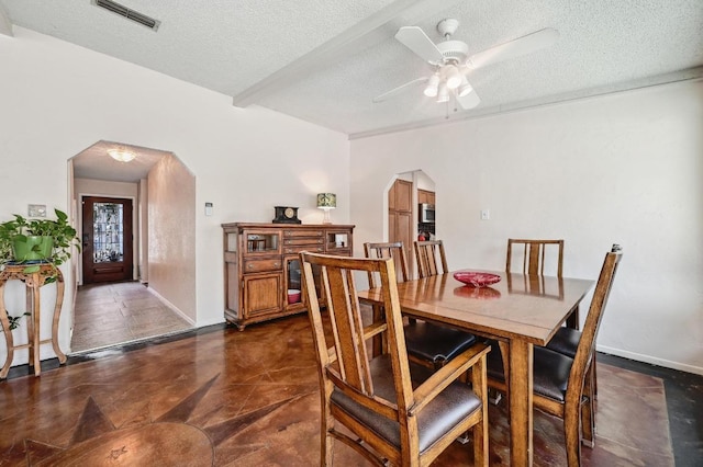 dining area with arched walkways, visible vents, a textured ceiling, and ceiling fan