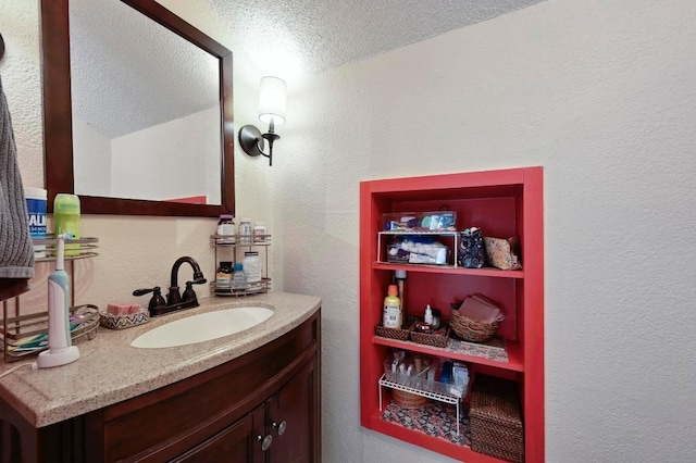 bathroom featuring vanity, a textured wall, and a textured ceiling