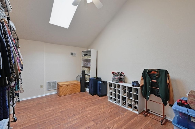 interior space with a stone fireplace, wood finished floors, visible vents, and a ceiling fan