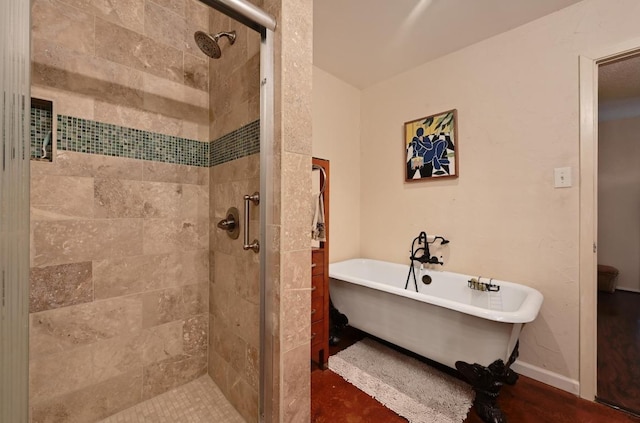 bathroom featuring baseboards, a freestanding bath, and a shower stall