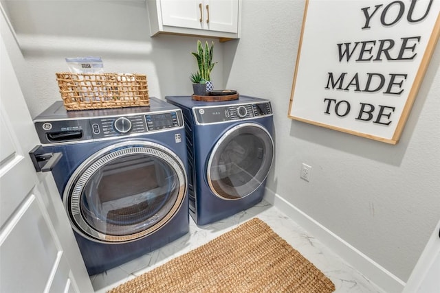 laundry area featuring washer and dryer, baseboards, marble finish floor, and cabinet space