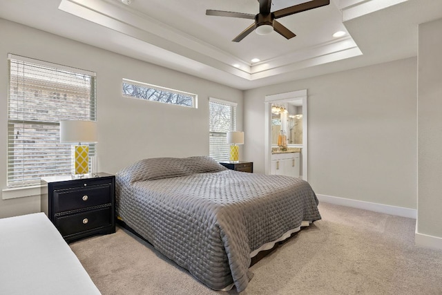 bedroom featuring light carpet, a tray ceiling, ensuite bath, recessed lighting, and baseboards