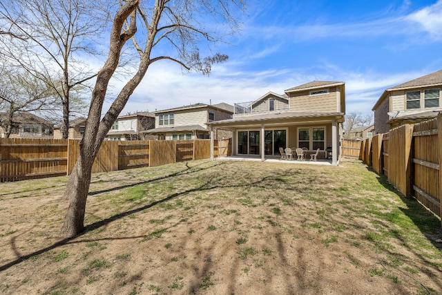 rear view of property featuring a lawn, a fenced backyard, and a patio area