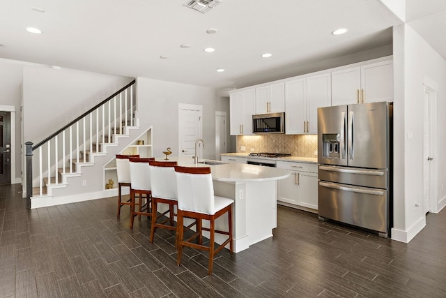 1050 Kenney Fort Xing Unit 24, Round Rock, TX 78665 - kitchen with stainless steel appliances, a sink, dark wood-style flooring, an island with sink, and tasteful backsplash