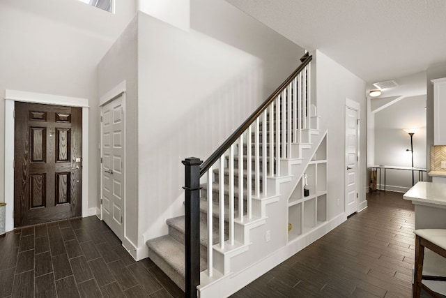 stairway featuring visible vents, baseboards, and wood finish floors