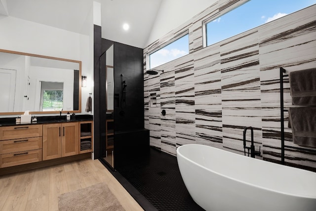 bathroom featuring vanity, a soaking tub, plenty of natural light, vaulted ceiling, and a walk in shower