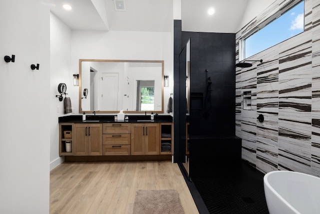 bathroom with visible vents, a walk in shower, wood finished floors, double vanity, and a soaking tub