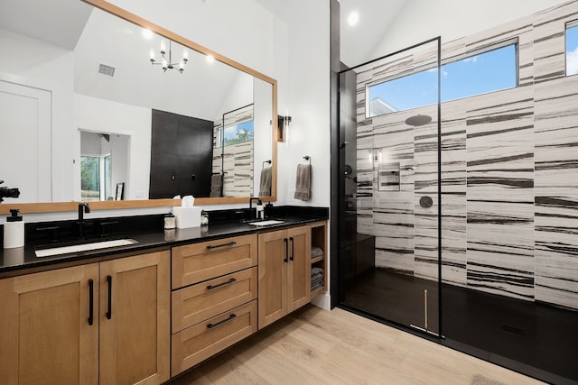 bathroom featuring vaulted ceiling, tiled shower, wood finished floors, and a sink