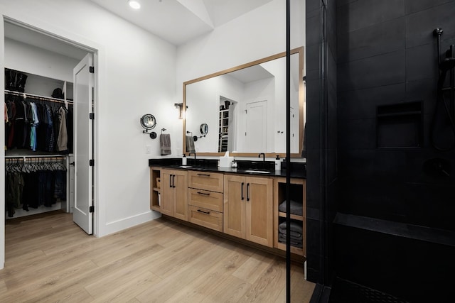 bathroom featuring double vanity, a sink, a walk in closet, and wood finished floors