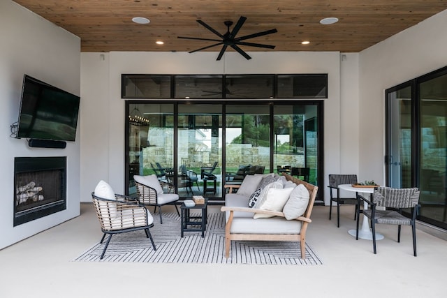 view of patio with an outdoor living space with a fireplace and a ceiling fan