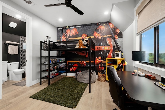 bedroom with ensuite bath, wood finished floors, visible vents, and ceiling fan