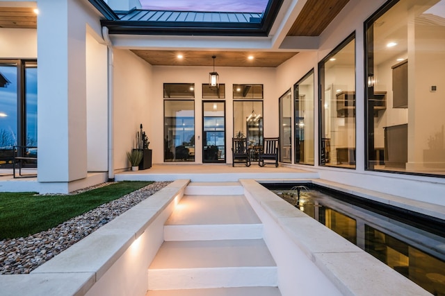 doorway to property featuring a standing seam roof, metal roof, and stucco siding