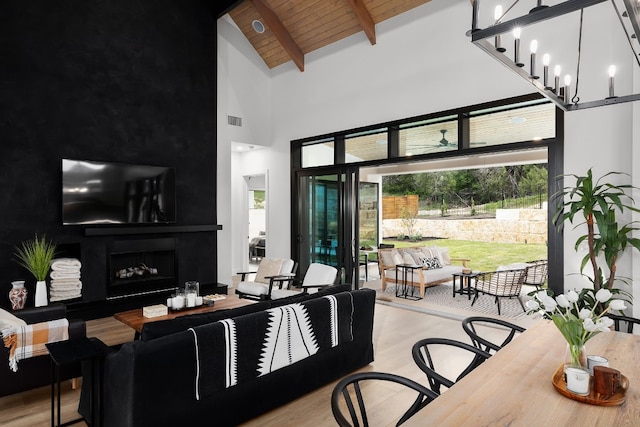 living area featuring wood finished floors, visible vents, beam ceiling, a fireplace, and wooden ceiling