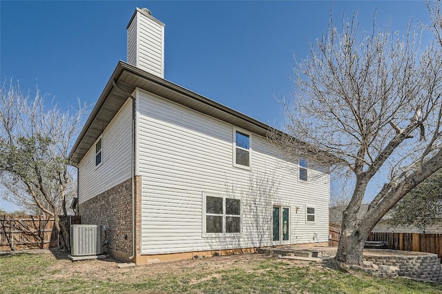 rear view of house featuring a patio, central AC unit, a fenced backyard, a chimney, and brick siding