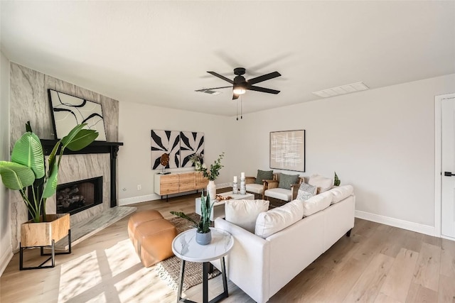 living area featuring a fireplace, wood finished floors, visible vents, and ceiling fan