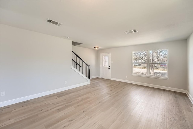 interior space with stairway, wood finished floors, visible vents, and baseboards