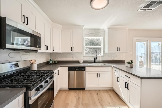 849 Satellite Vw, Round Rock, TX 78665 - kitchen with stainless steel appliances, a sink, light wood-type flooring, a peninsula, and white cabinets