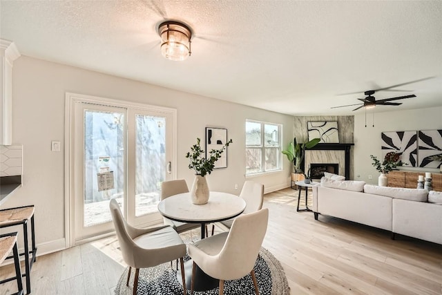 849 Satellite Vw, Round Rock, TX 78665 - dining space with a fireplace, ceiling fan, light wood-style floors, a textured ceiling, and baseboards