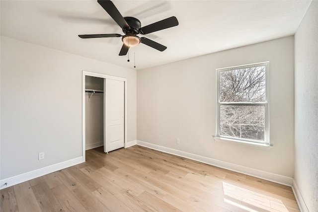 unfurnished bedroom featuring a closet, baseboards, light wood-style floors, and a ceiling fan