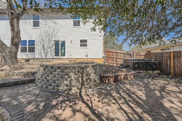 back of property featuring a patio, a fenced backyard, and a hot tub