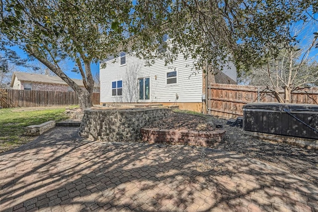 back of property featuring a patio area, a hot tub, and a fenced backyard