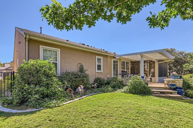 rear view of house with stucco siding, a yard, and a pergola