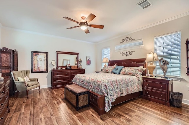 bedroom with wood finished floors, visible vents, and ornamental molding