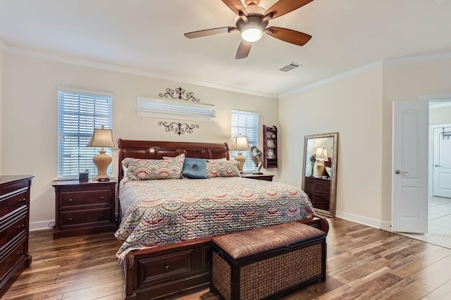 bedroom featuring visible vents, ornamental molding, a ceiling fan, dark wood finished floors, and baseboards