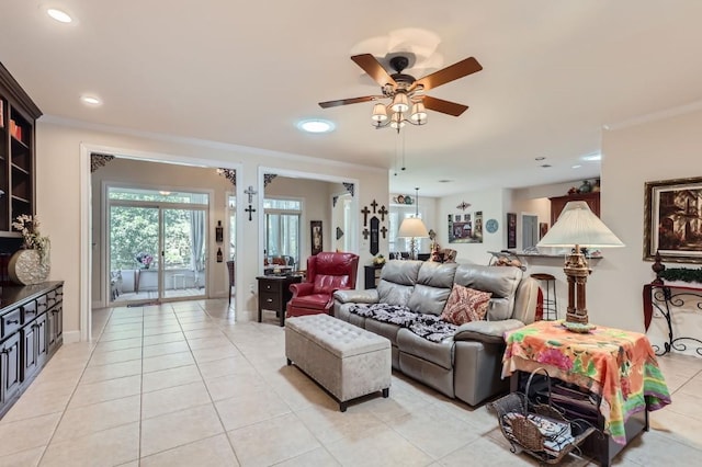 living area featuring light tile patterned floors, a ceiling fan, and crown molding