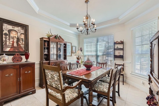 dining area with baseboards, a raised ceiling, a chandelier, and crown molding