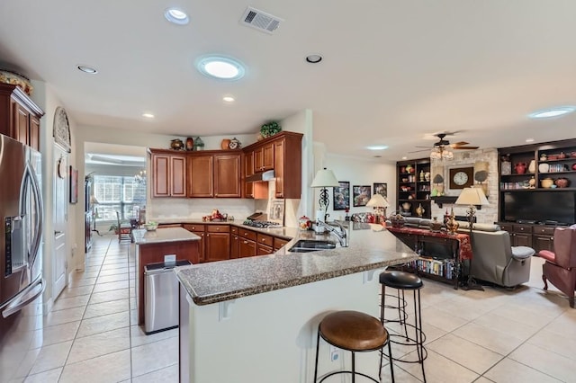 kitchen with visible vents, a sink, open floor plan, stainless steel appliances, and a peninsula