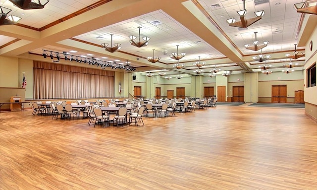 misc room featuring wood finished floors, visible vents, a high ceiling, ornamental molding, and a raised ceiling