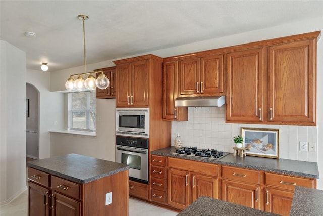 kitchen featuring under cabinet range hood, appliances with stainless steel finishes, dark countertops, and arched walkways