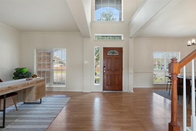 foyer entrance with ornamental molding, wood finished floors, an inviting chandelier, baseboards, and stairs