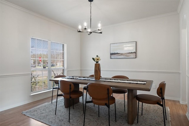 dining room featuring crown molding, a notable chandelier, wood finished floors, and baseboards