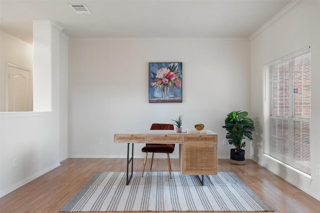 office space with visible vents, baseboards, crown molding, and light wood-style floors