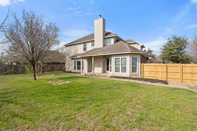 back of house with a yard, a fenced backyard, and a chimney