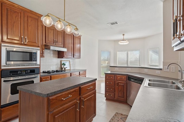 kitchen with visible vents, a sink, under cabinet range hood, tasteful backsplash, and appliances with stainless steel finishes