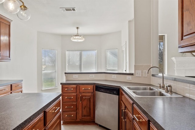 kitchen with visible vents, a sink, hanging light fixtures, stainless steel dishwasher, and dark countertops