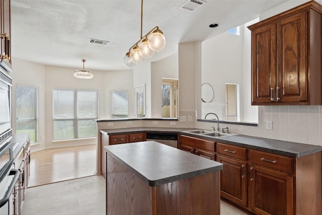 kitchen featuring a sink, visible vents, dark countertops, and backsplash