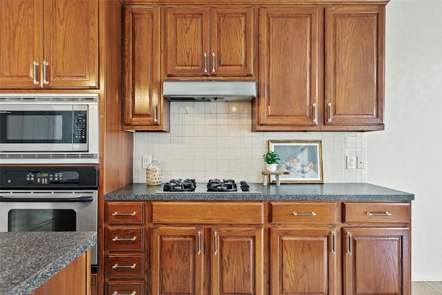 kitchen with stainless steel appliances, brown cabinets, extractor fan, and dark countertops