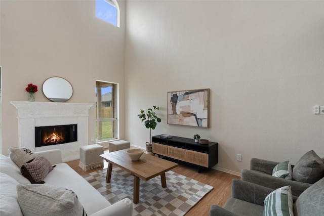 living area featuring baseboards, plenty of natural light, light wood-style flooring, and a fireplace