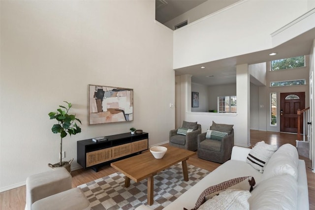 living area featuring visible vents, wood finished floors, and a towering ceiling